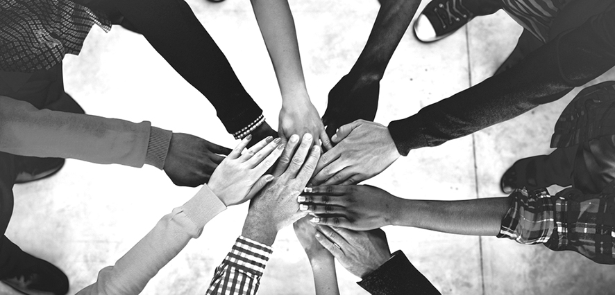 Black and White photo of hands join together. Different skin tones.