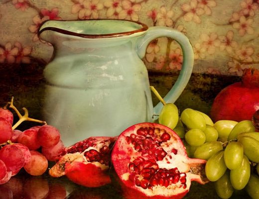 Small jug surrounded by fruit - grapes, pomegranate and apples