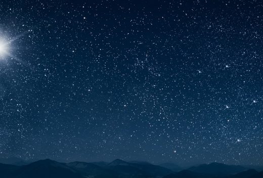 Dark navy blue sky with an array of stars. A large star shines to the left over a think strip of dark land at the bottom of the pic